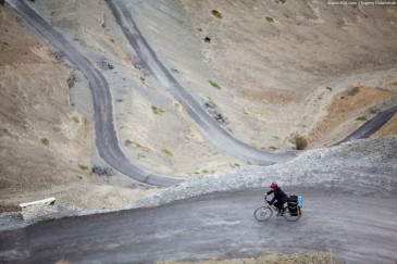 Cyclist on winding road. Himalayas, Ladakh, India