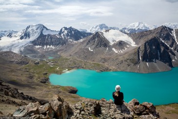 Traveller sitting and looking at Ala-Kul Lake. Tien Shan Mountains, Kyrgyzstan