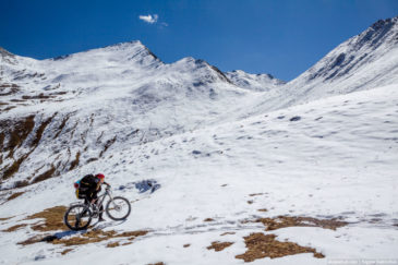 Cyclist carring bike to snowy pass